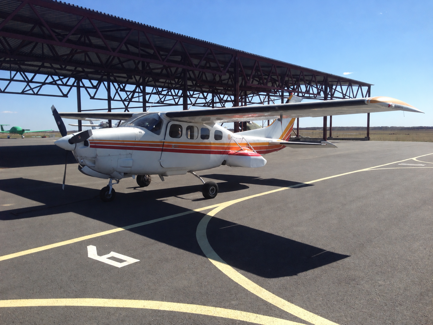 Light twin-engine aircraft on an apron in front of an open hangar