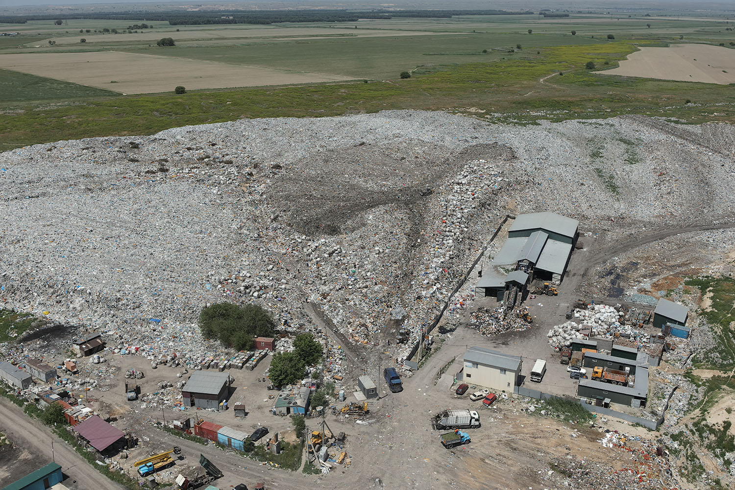 Oblique aerial view of an active landfill face with sorting sheds and haul road